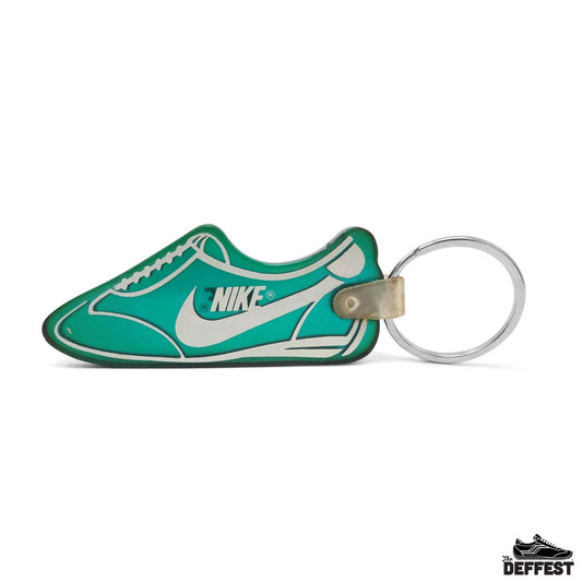 A Nike sneaker-shaped keychain in a vibrant teal green and white, featuring a silver metal split ring and a small gold-toned rivet, shown on a plain white background.