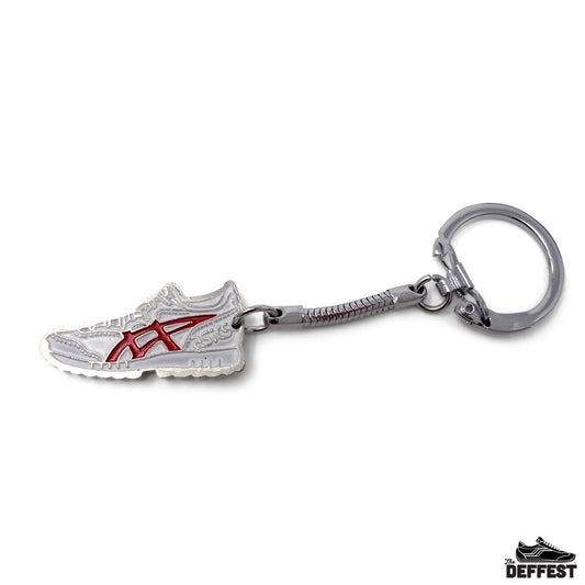A metallic asics tiger keychain shaped like a white and red running shoe, attached to a silver split ring and textured metal connector, shown on a plain white background.